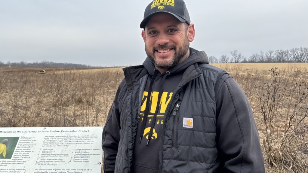 Tony Senio standing in from of the Prairie Restoration sign with the dormant prairie in the background
